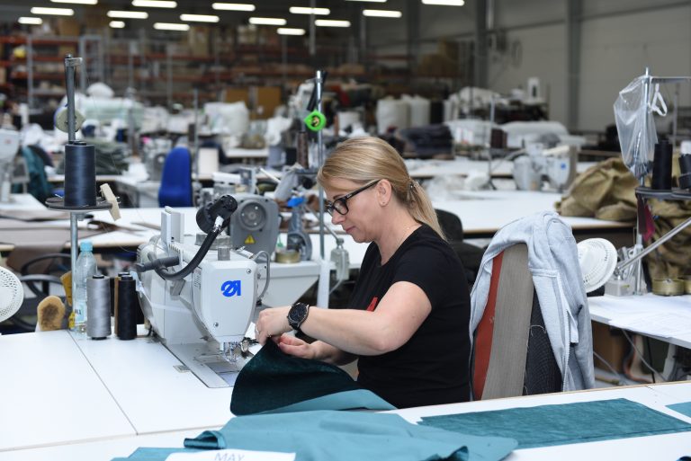 Polaszek Meble Kobieta szyjąca tkaninę w industrialnym miejscu pracy przy użyciu Polaszka mebli. Chojnice