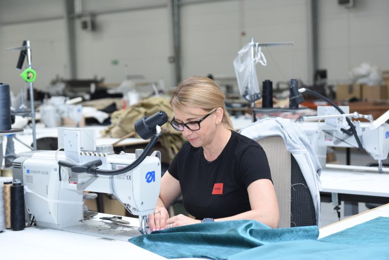 Polaszek Meble Kobieta korzystająca z maszyny do szycia w industrialnym miejscu pracy w firmie Meble Chojnice. Chojnice