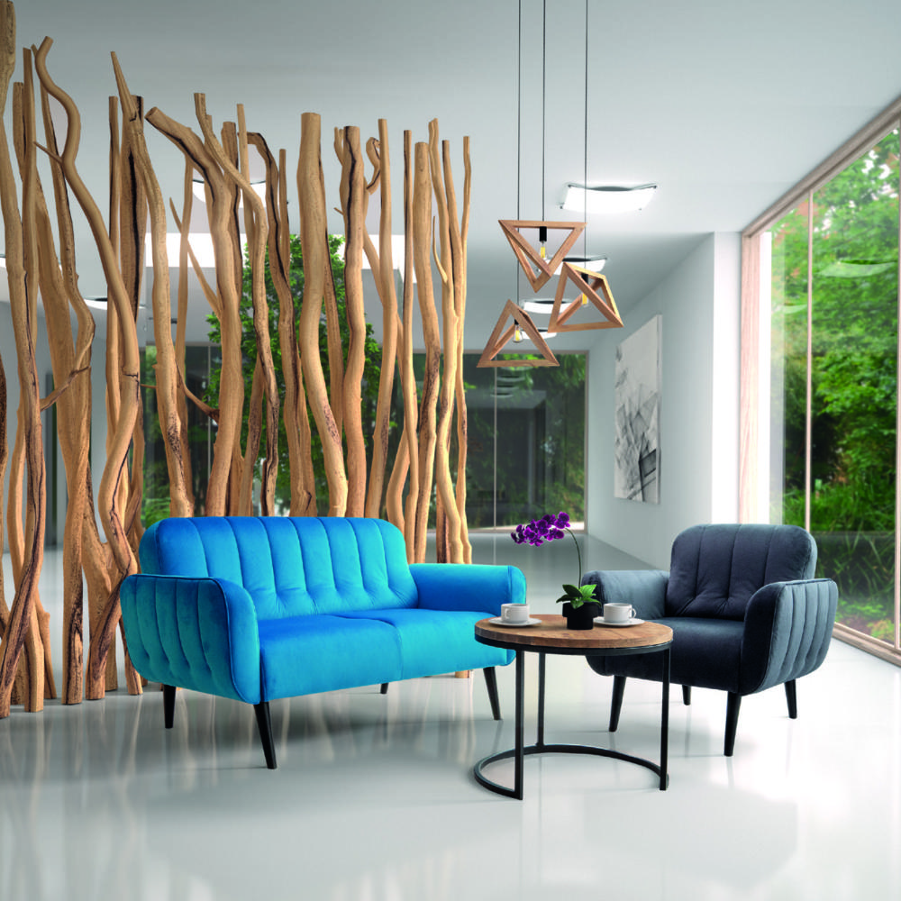 Polaszek Meble Nowoczesny salon z niebieską pikowaną sofą, czarnym fotelem, drewnianym stolikiem bocznym Polaszek meble i dużymi ozdobnymi gałęziami na ścianie okna. Chojnice